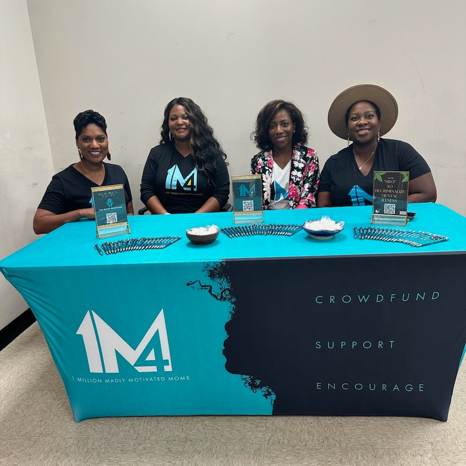 Four women sitting an informational table.