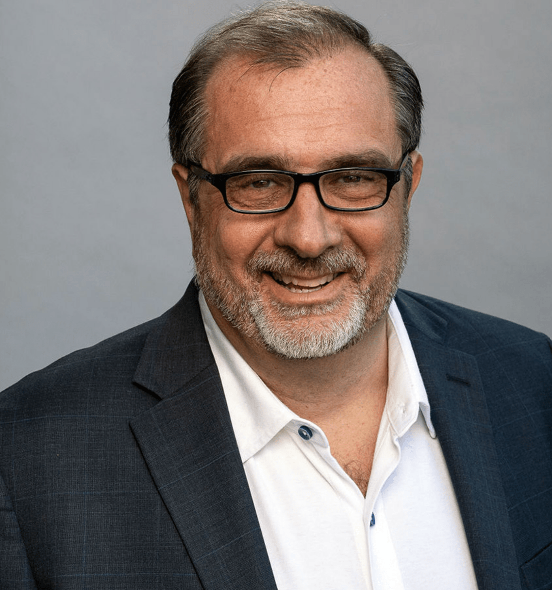middle aged white man with glasses, black blazer and white button down shirt. 